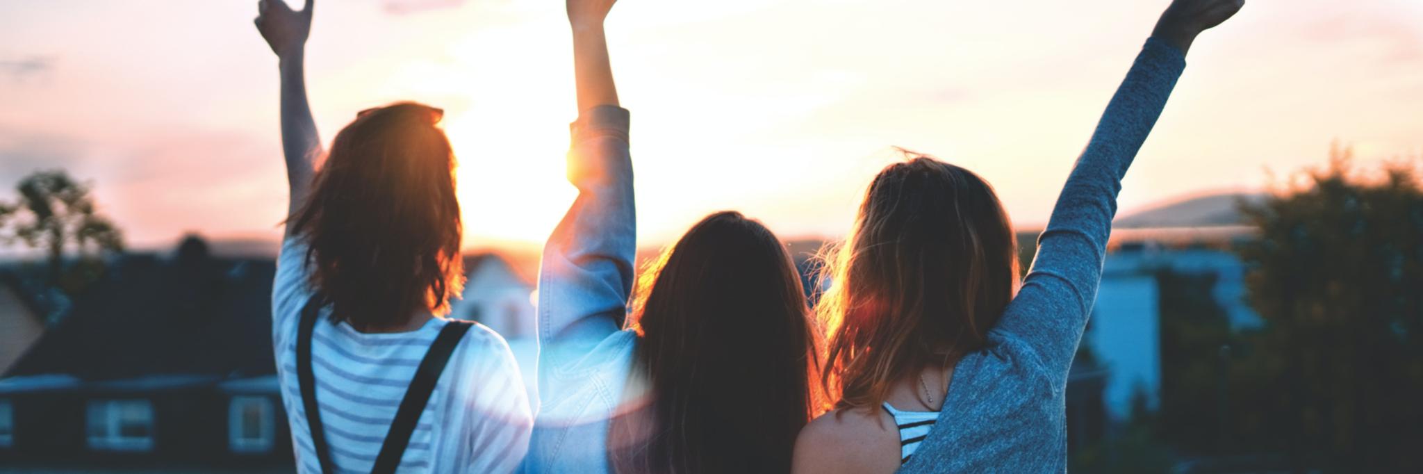 Vor einem Sonnenuntergang sind man eine Gruppe junger Menschen die gut gelaunt die Hände in den Himmel heben (c) Simon Maage auf Unsplash Vor einem Sonnenuntergang sind man eine Gruppe junger Menschen die gut gelaunt die Hände in den Himmel heben